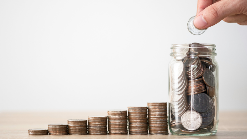 Coins tacked next to jar filled with coins