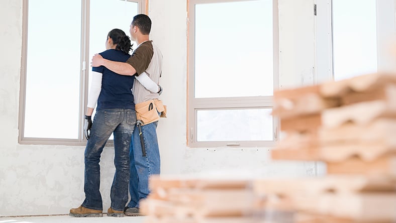 A couple taking a break from renovating their home and looking out the window